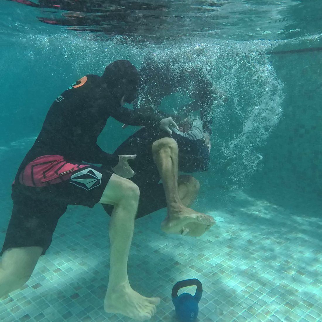 An instructor guiding a student through a weighted breath-hold in the pool