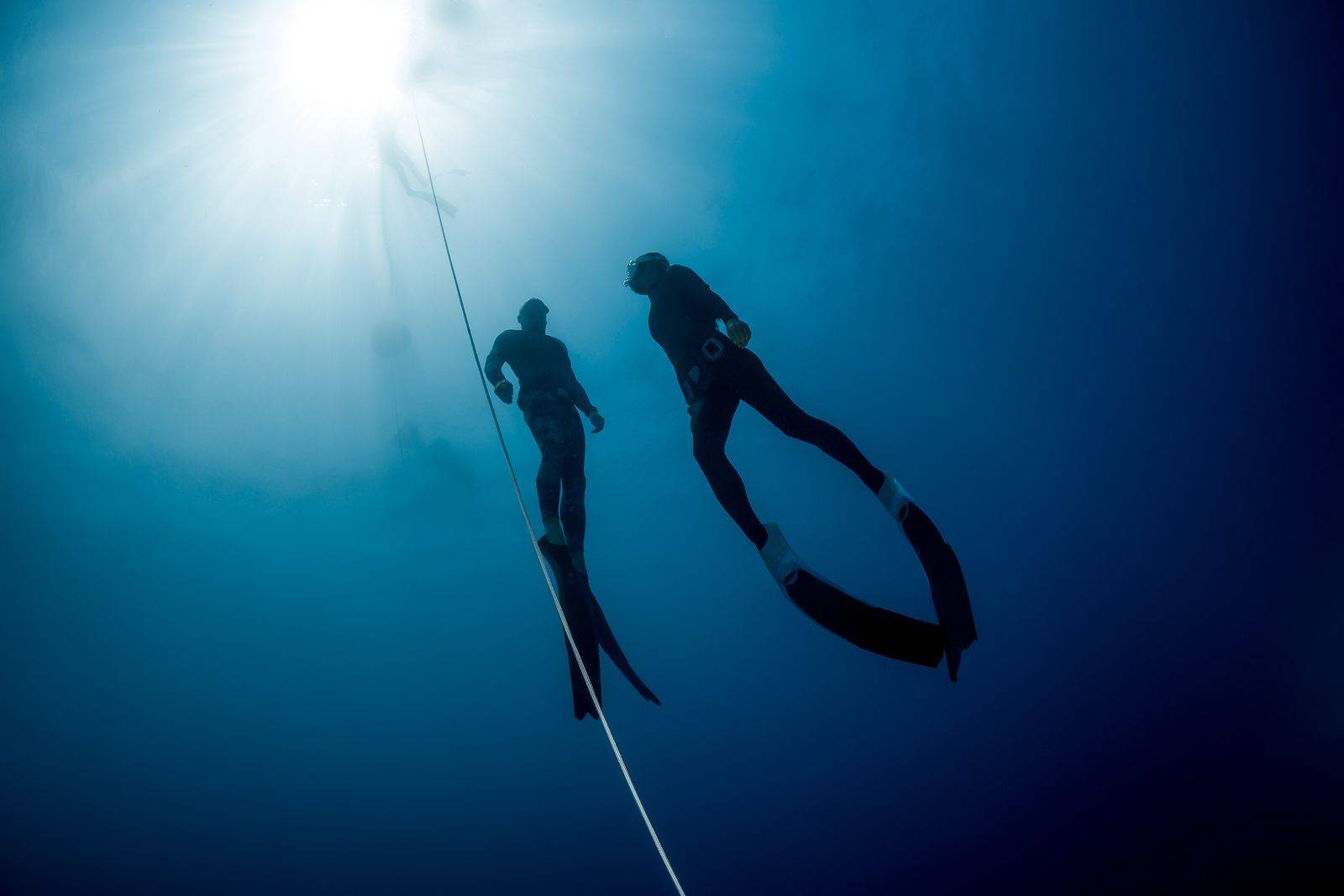 Two freedivers ascending the line towards the sun