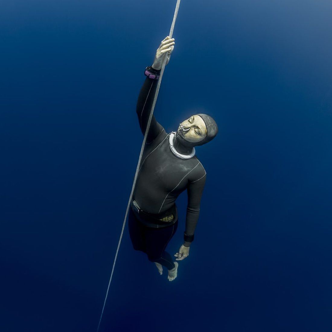 A freediver ascending hand over hand on the line